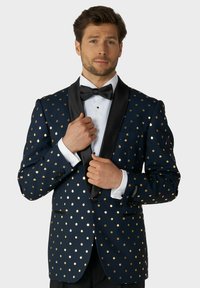 Námornícky blazer s zlatými bodkami, s čiernym saténovým šálovým golierom, jedným gombíkom a prednou vreckom. Pod ním biela košeľa.