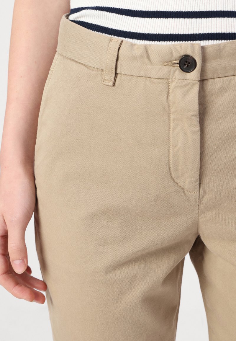 Beige Baumwollhosen mit Knopfverschluss, einer einzelnen Vorderasche und glatter Textur. Der Bund verfügt über Gürtelschlaufen und keine sichtbaren Verzierungen.