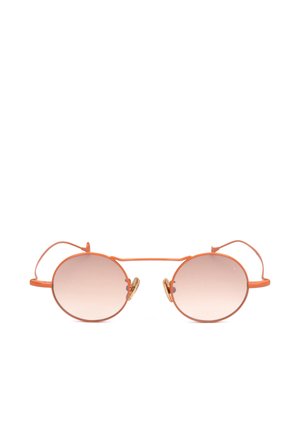 Occhiali da sole rotondi con sottile montatura metallica arancione e lenti sfumate marrone chiaro su sfondo bianco.