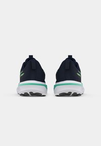 Navy athletic shoes with textured fabric, green accents, and white soles. Features a padded collar and rear pull tab for easy wear.
