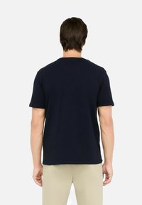 T-shirt in cotone blu navy con maniche corte e colletto rotondo, che presenta un design semplice e una texture liscia, vista da dietro.