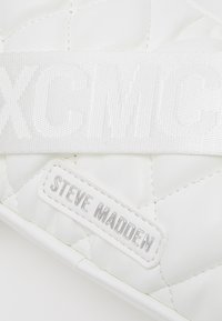 Borsa in ecopelle bianca trapuntata con una ampia tracolla intrecciata, decorata con un marchio impressa e un'etichetta logo in tono argento.