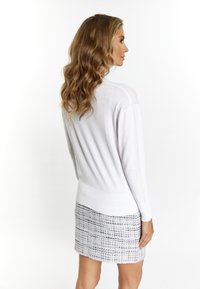 Witte, lichte sweater met een casual pasvorm, geribde zoom en lange mouwen, gecombineerd met een textuur rok in blauw en wit.