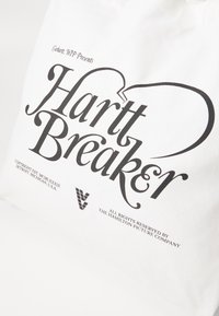 Vit canvas toteväska med stor svart text som säger "Hartt Breaker." Inkluderar mindre svart text och en grafisk bild nedan.