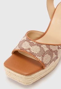 Sandalii cu toc wedge, cu un exterior din piele artificială maro și o curea țesută cu un model texturat, neutru. Dispun de o platformă din sfoară naturală. Design cu vârf pătrat.