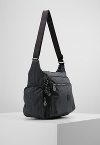 Gray fabric shoulder bag with a smooth texture, featuring a striped strap, two zippered pockets, and a circular logo detail.