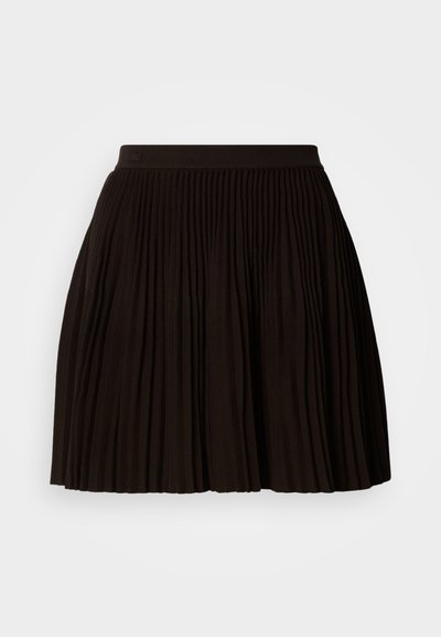 Jupe plissée noire avec une surface texturée, dotée d'une large ceinture élastique. Le design présente des plis verticaux pour un look structuré.