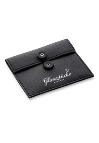 Juodas odinis vokelį primenantis piniginė su tekstūruota paviršiumi, dviem snapeliais, ir baltu logotipu "Glanzstücke München" priekyje.