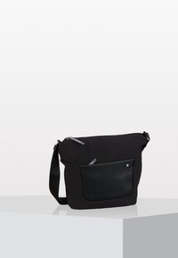 Borsa a tracolla nera con tracolla regolabile, tasca zip frontale e dettagli in pelle liscia, esposta su una superficie bianca.
