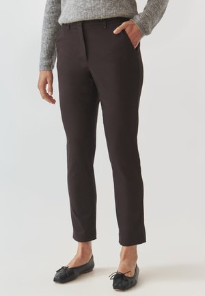 Black, slim-fit trousers with a smooth texture, front pockets, and a mid-rise waist. Paired with black ballet flats and grey knit sweater.
