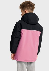 Veste colorée avec une partie supérieure noire et une moitié inférieure rose. Dotée d'une capuche et d'une bande réfléchissante dans le dos. Texture lisse.