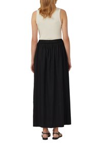 Black, flowy maxi skirt with an elastic waistband, paired with a fitted, ribbed, beige tank top. Simple design, cotton material.
