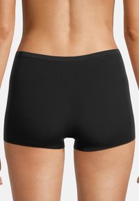 Svarta stretchshorts med en mjuk yta och sömlös design, som har ett lågt midjeband och måttlig täckning vid benen.