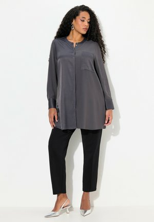 Chemise en satin grise à manches longues avec une poche avant, associée à un pantalon noir ajusté et des escarpins argentés à bout pointu.