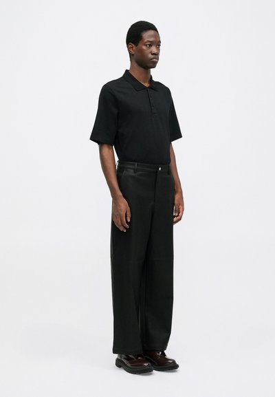 Black polo shirt with short sleeves, paired with high-waisted wide-leg black trousers and brown lace-up boots. Minimalist design.