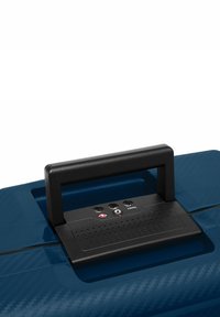 Valigia rigida blu con una finitura texture, dotata di un manico nero e di una serratura, e tre serrature a combinazione su un pannello di controllo rialzato.