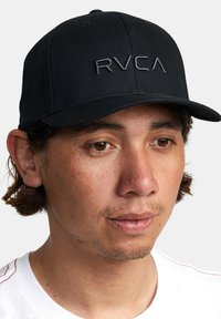 Black baseball cap with a structured design, featuring raised RVCA logo in gray. Fabric appears smooth with a slight sheen.