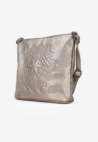 Bolso de hombro de cuero plateado metálico con un diseño geométrico texturizado, cierre de cremallera y correa ajustable. Superficie lisa con costura decorativa.