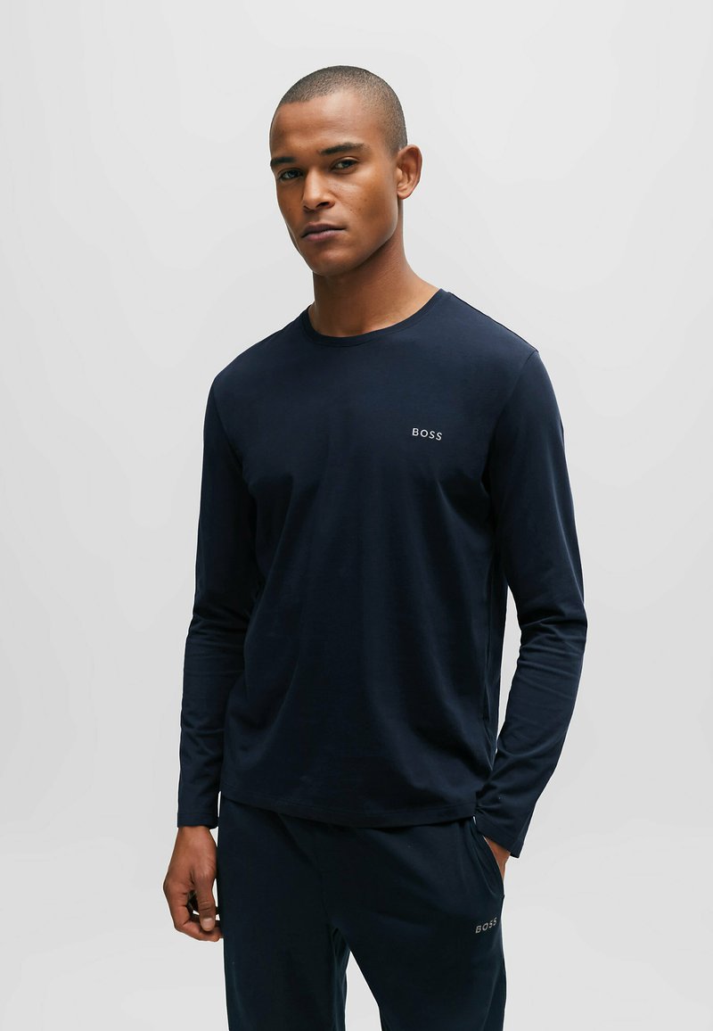 Marineblaues Langarm-T-Shirt mit Rundhalsausschnitt und dezentem Logo auf der Brust, aus weichem, leichtem Stoff gefertigt.