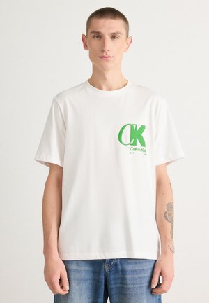 Witte katoenen T-shirt met een groen "CK" logo op de linkerkant van de borst. Korte mouwen, ronde halslijn, losse pasvorm en een gladde textuur.