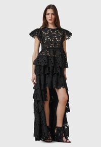 Black lace dress featuring a peplum design, short ruffled sleeves, and a tiered high-low hem with intricate cut-out patterns.