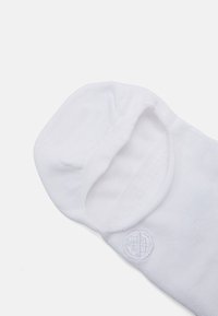 White ankle sock with ribbed texture, soft fabric, and a circular logo detail. The opening is elasticated for a snug fit.