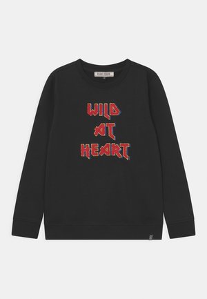 Sudadera negra de manga larga, con la frase "WILD AT HEART" bordada en colores variados y estilo estilizado en el frente. Hecha de tela suave.