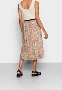 Bloemen midi-jurk met een crèmekleurige basis en oranje en blauwe bloemen, elastische tailleband en vloeiende stof, gecombineerd met zwarte sandalen met straps.