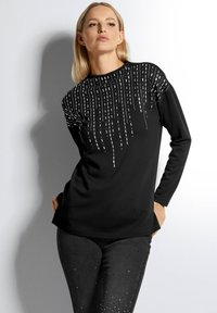 Zwarte lange mouwen top met een textuurontwerp en verticale witte accenten. Het materiaal lijkt glad, met een ontspannen pasvorm en een ronde halslijn.