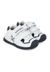 Zapatos sintéticos blancos con acentos negros, que cuentan con dos correas de Velcro, puntera redondeada y una suela de goma texturizada para mayor tracción.