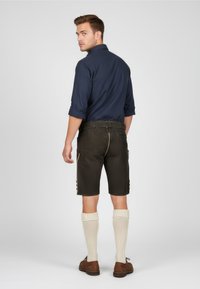 Navy shirt, dark brown shorts, and beige knee socks; shorts feature side buttons and gold stitching, giving a traditional look.