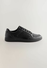 Svart sneaker med slät läder och strukturerade meshpaneler, rund tåform, platt sula och snörning med sex öglor.