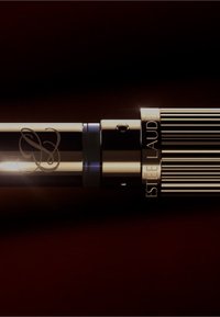 Penna retrattile nera e oro con fusto testurizzato, logo incisa e cappuccio a strisce, che mostra un design elegante e moderno.