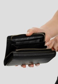 Billetera de cuero negro texturizado abierta, mostrando múltiples compartimentos, cremallera dorada y un acento de tachuelas en la parte frontal.