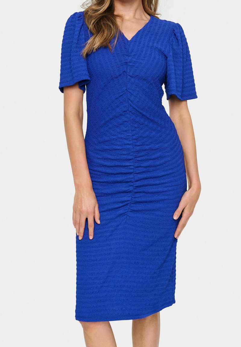 Femme portant une robe midi bleu roi texturée ajustée avec des manches courtes bouffantes et un décolleté en V.