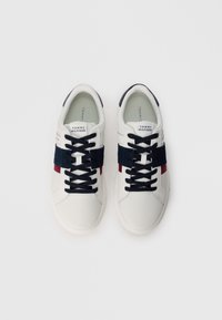 White leather sneakers with navy blue and red horizontal stripes, black laces, and textured accents; branded tongue labels are visible.