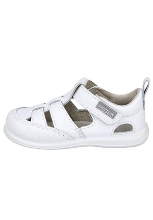 Sandalia blanca de niño con puntera cerrada, con tira de Velcro etiquetada "zapryflex" y detalles recortados en el lateral y la parte delantera para mayor transpirabilidad.