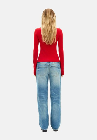 Rød ribbet langærmet top kombineret med lyseblå højttaljede viddebukser i denim, set bagfra med et klassisk denimdesign.