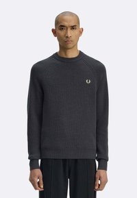 Maglione grigio scuro con texture a coste, collo rotondo e maniche raglan. Presenta un piccolo logo ricamato sul petto a sinistra.