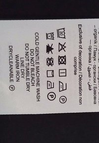 Étiquette de soin indiquant les instructions de lavage : lavage en machine délicat à froid 30°C, ne pas blanchir, ne pas sécher en sèche-linge, sécher à l’air libre, repassage chaud, nettoyage à sec possible.
