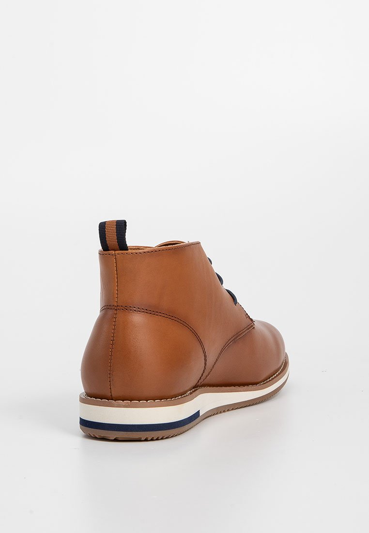 Braune Lederknöchelstiefel mit schwarzen Schnürsenkeln, gestreiftem Stoff-Anziehschlaufen, weißer Sohle mit blauer Linie, von der Rückseite auf weißem Hintergrund fotografiert.