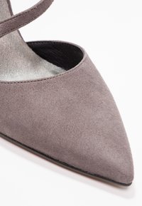 Chaussure à talon haut en suédine grise avec un embout pointu, présentant une silhouette élégante et un accent intérieur métallique. S'élève grâce à un design minimaliste.