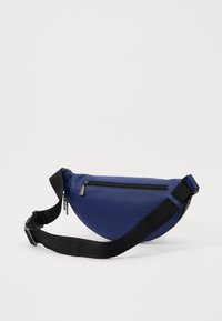 Zila ādas plecu soma ar noapaļotu formu, melnu regulējamu siksnu un rāvējslēdzēja kabatu priekšpusē. Ar teksturētu virsmas apdari.