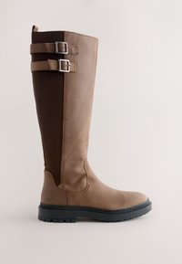 Stivale alto in pelle marrone con pannello elastico posteriore scuro, due cinturini regolabili con fibbia in cima e suola spessa nera con carrarmato.