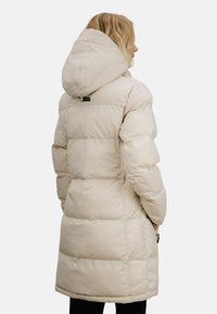 Vattert jakke i lys beige med romslig hette, quiltet design og sidelommer, med en lett innsnevret midje for en skreddersydd passform.