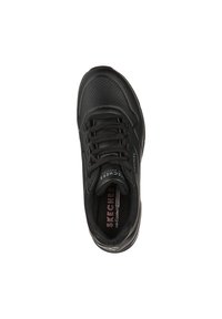 Černá sportovní bota s hladkým koženým svrškem, perforovanými částmi, šněrovacím designem, polstrovanou podrážkou a logem na jazyku.