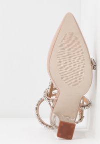 Transparent häl sanda med en ljusrosa ovandel, dekorerad med klara remmar och rhinestones accent; har en strukturerad gummisula.