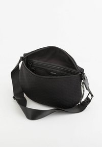 Schwarze Tasche aus strukturiertem Material mit einem Wabenmuster, Reißverschluss und einem verstellbaren Tragegurt mit einem bunten Akzent.