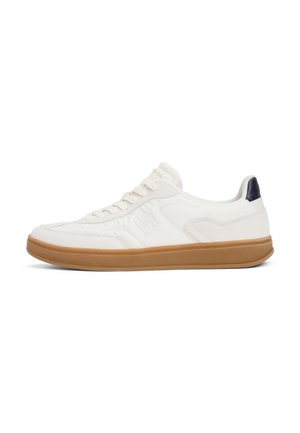 Biały niski sneaker z jasnobrązową podeszwą, wiązaniem na sznurówki, subtelnymi szwami i ciemnogranatowym paskiem na pięcie.