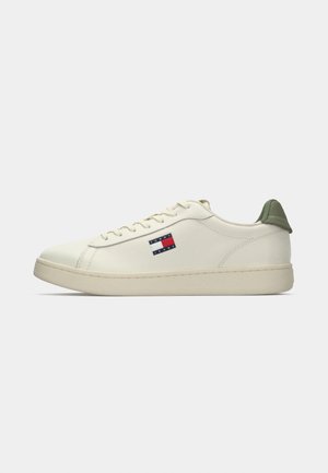 Weißer Sneaker mit grünem Fersenakzent, glattem Synthetik-Obermaterial, runder Zehenform, Schnürverschluss und Logo-Patch mit roten, weißen und blauen Streifen.